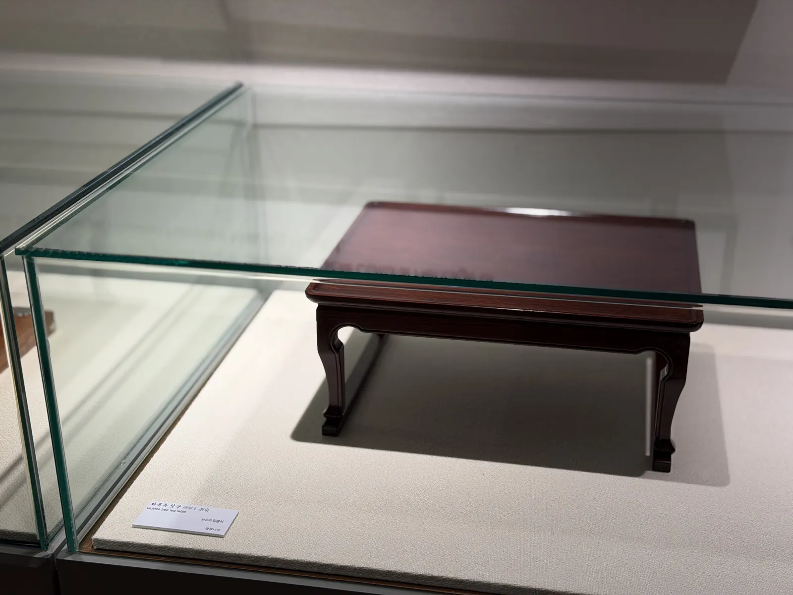 A low dark table in a glass case